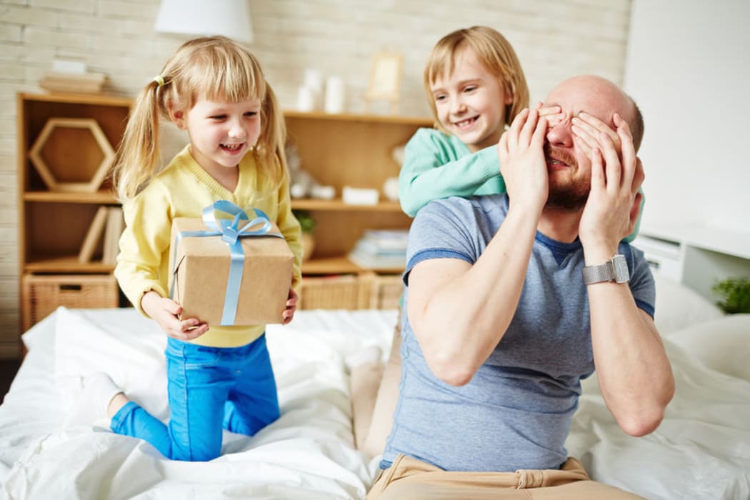 A photo of daughters giving their father a present