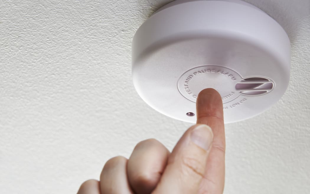 Close Up Of Hand Testing Domestic Smoke Alarm