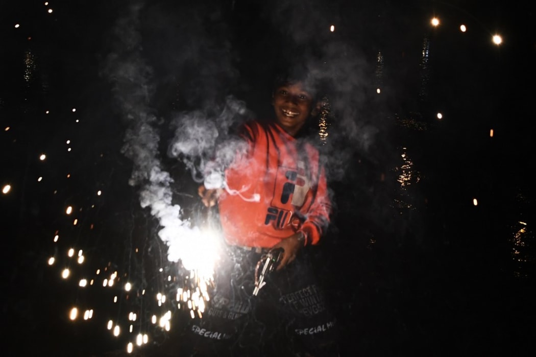 A boy lights a sparkler during Diwali, the Hindu Festival of Lights, in New Delhi on November 14, 2020. (Photo by Sajjad HUSSAIN / AFP)