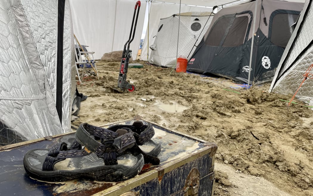 A pair of Teva sandals are seen on a chest in the middle of tents sitting in a muddy desert plain on September 3, 2023, after heavy rains turned the annual Burning Man festival site in Nevada’s Black Rock desert into a mud pit. Tens of thousands of festivalgoers were stranded September 3, in deep mud in the Nevada desert after rain turned the annual Burning Man gathering into a quagmire, with police investigating one death.
Video footage showed costume-wearing "burners" struggling across the wet gray-brown site, some using trash bags as makeshift boots, while many vehicles were stuck in the sludge. (Photo by Julie JAMMOT / AFP)