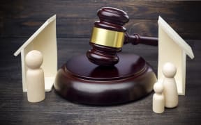 Gavel showing separation of family and house on dark wooden table