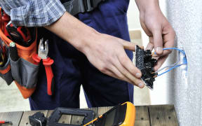 Young electrician at work on switches and sockets of a residential electrical installation.