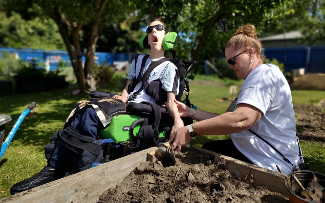 Midge Walesby (16) works in the soil with help from kaiawhina (learning assistant).