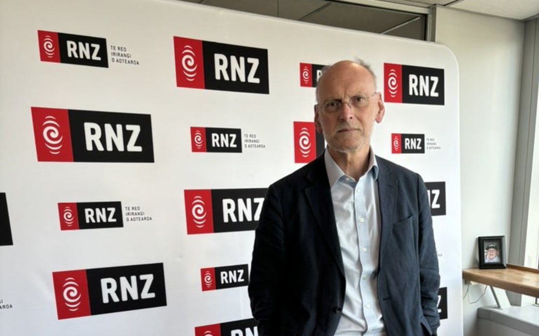 Nigel stands in front of an RNZ photo wall.