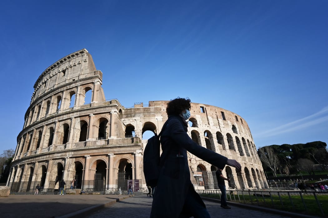 A tourist wearing a respiratory mask as part of precautionary measures against the spread of the new COVID-19 coronavirus, walks past the closed Colisseum monument in Rome.
