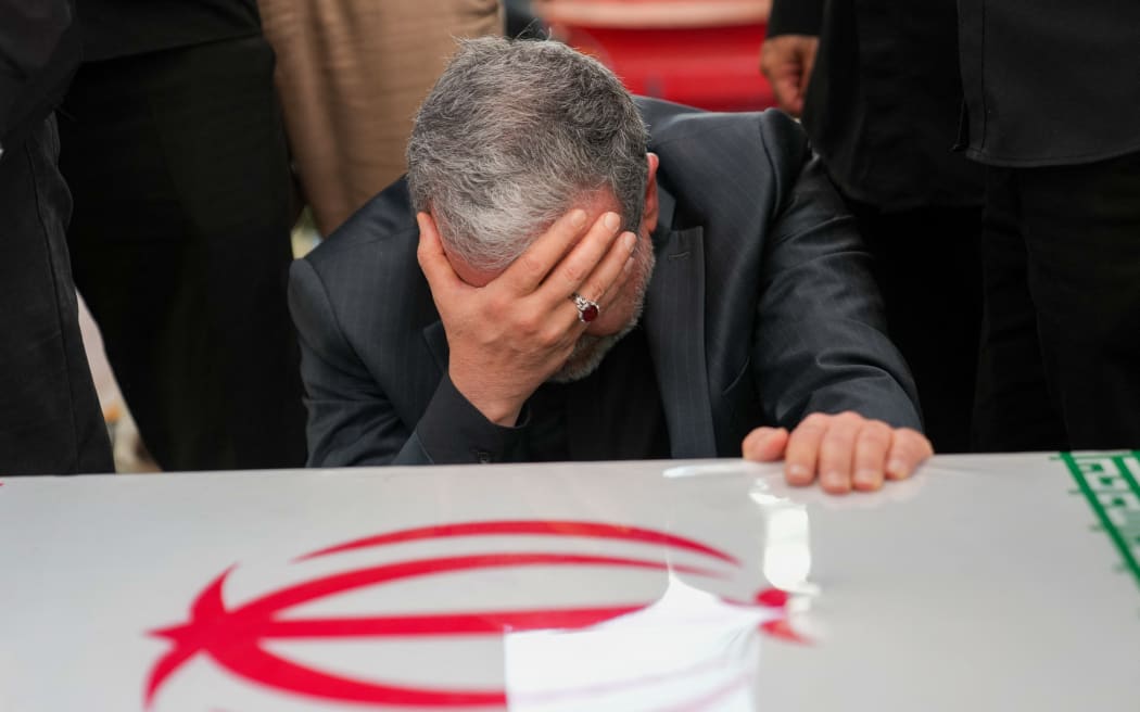 This handout picture provided by the Iranian foreign ministry shows Iran's Foreign Minister Abbas Araghchi mourning next to the coffin of Iranian Revolutionary Guards commander Hossein Salami, who was killed during Israeli strikes on the first day of the war, during a state funeral procession at Enghelab (Revolution) Square in the capital Tehran on June 28, 2025. Iran began a state funeral service on June 28 for around 60 people, including its military commanders, killed in its war with Israel, after Tehran's top diplomat condemned  Donald Trump's comments on supreme leader Ali Khamenei as "unacceptable". (Photo by Iranian Foreign Ministry / AFP) / === RESTRICTED TO EDITORIAL USE - MANDATORY CREDIT "AFP PHOTO / HO / IRANIAN FOREIGN MINISTRY" - NO MARKETING NO ADVERTISING CAMPAIGNS - DISTRIBUTED AS A SERVICE TO CLIENTS ===
