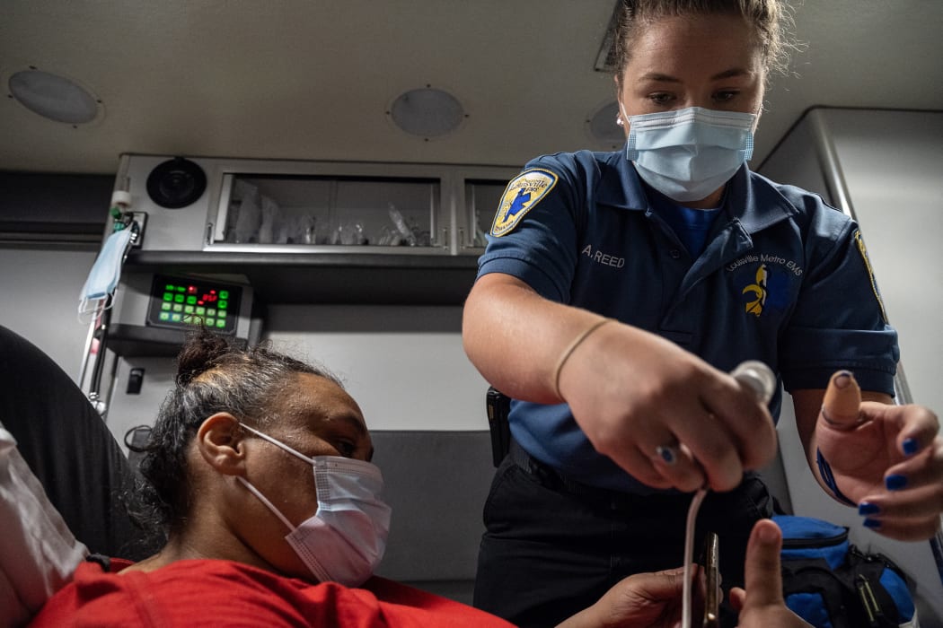 A Louisville medic helps a woman experiencing a Covid-19 emergency. Louisville Metro EMS is experiencing a surge in patients needing emergency treatment and transport.