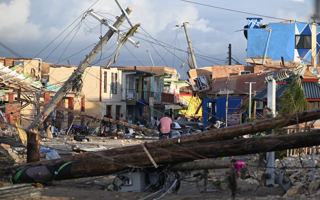 Electrical poles are down as a man bikes through the destroyed neighbourhood of North Street following the passage of Hurricane Melissa, in Black River, Jamaica.