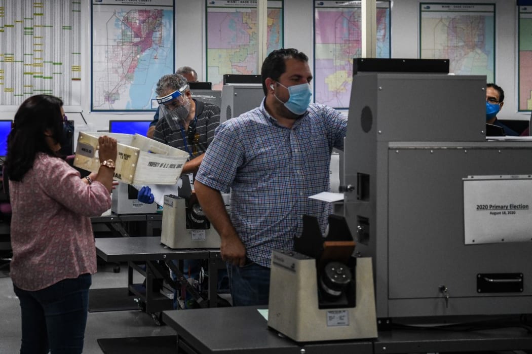 Employees of Miami-Dade Elections Department scan the votes for counting during Florida Primary Election amid the coronavirus pandemic, at Miami-Dade Elections Department in Miami, Florida on August 18, 2020.