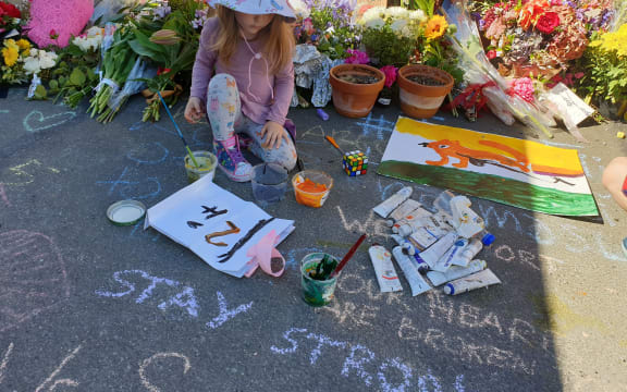 Ash Boraman-Ritchie paints a message outside Al Huda Mosque in Dunedin.