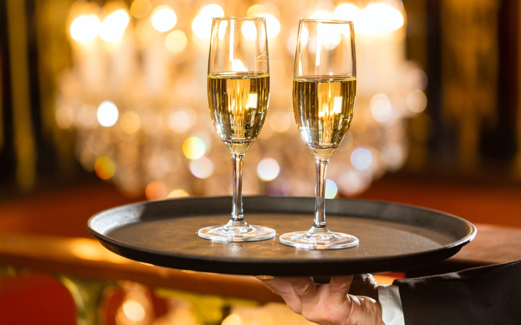A waiter holds two glasses of champagne, at a gala dinner (file).