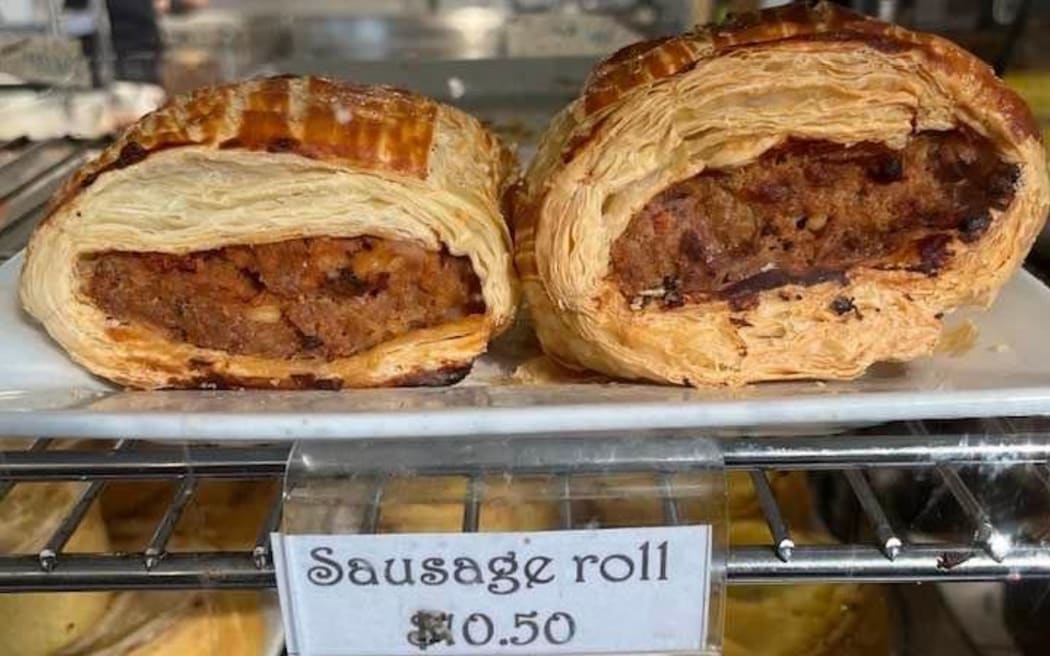 A sausage roll for sale in a cafe.