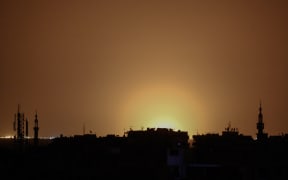 A photo taken from the rebel-held town of Douma shows flames rising in the distance which are believed to be coming from Damascus International Airport following an explosion.