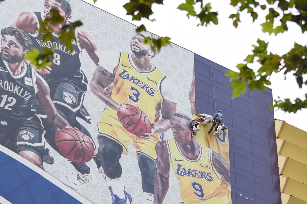 Workers tear down a poster promoting a game between Lakers and Brooklyn Nets of National Basketball Association (NBA) at Super Brand Mall in Shanghai, China, in 2019 after Houston Rockets general manager Daryl Morey's comments on Twitter about Hong Kong.