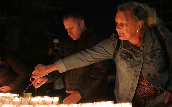 Christchurch City Councillor Yani Johansen (L) and vigil organiser Julie Abraham (R) light candles together.
