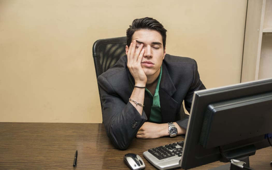 Man with head in hands in front of computer