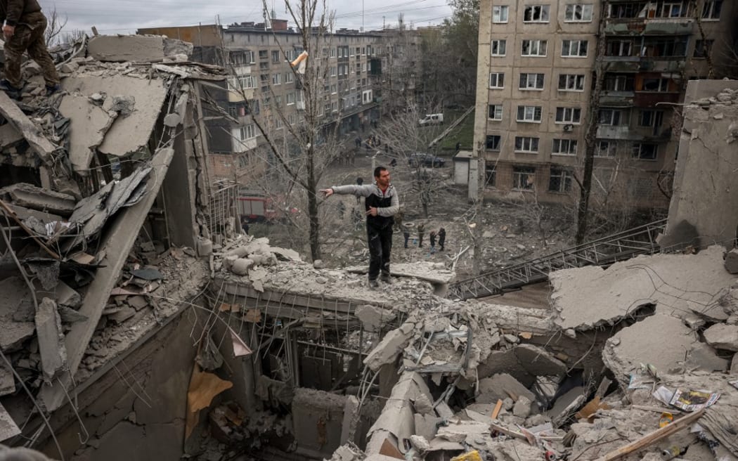 A volunteer gesticulates on top of a partially destroyed residential building after a shelling in Sloviansk, Donetsk region on April 14, 2023.