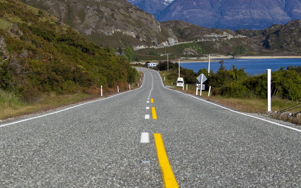An empty stretch of road in New Zealand's South Island, with mountains and a lake in the background