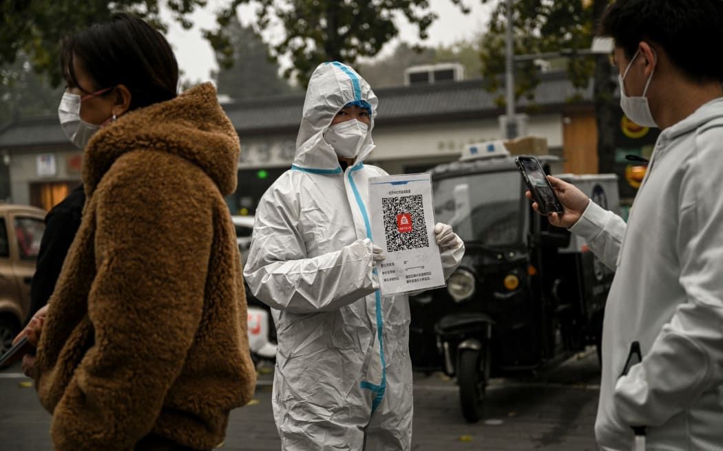A health worker holds up a QR code to scan as people queue to test for Covid-19 at a swab collection station in Beijing on 20 November 2022.