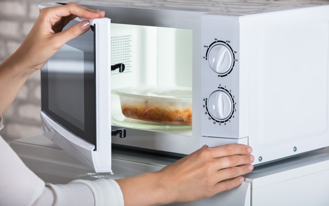 Woman's Hands Closing Microwave Oven Door And Preparing Food At Home