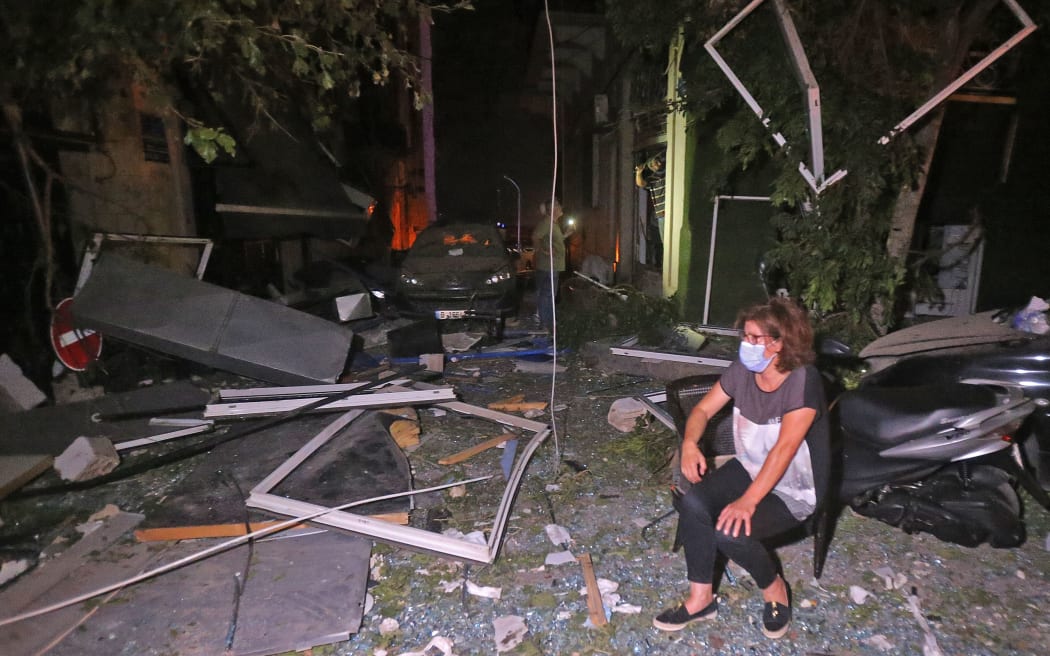 A woman wearing a mask due to the Covid-19  pandemic sits amid rubble in the Gemmayzeh area in the centre of Lebanon's capital Beirut on August 4, 2020, following a massive explosion at the nearby port of Beirut.