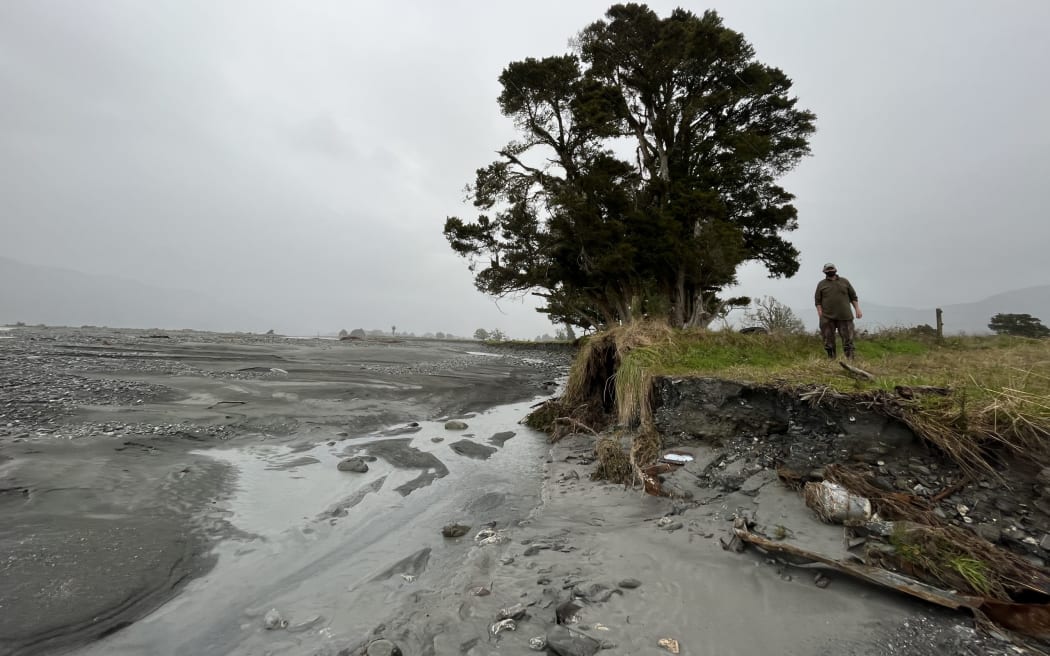 Long-time Waiho Flat farmer Richard Molloy stands on the edge of land owned by Peter Dennehy being eaten away while the landowners await a decision on their future.