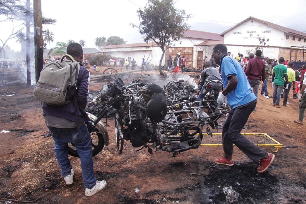 Two men carry the remains of a burnt out motorbike after a fuel tanker exploded on August 10, 2019, in Morogoro.