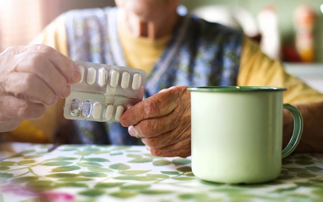 A person about to consume cold medications with a cup of tea