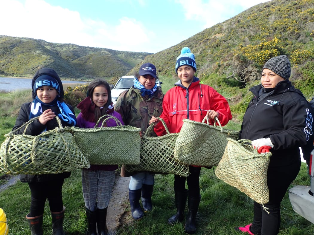 Perzia-Rose, Ryah-Jane, Ada, Harmony and Ngahuia Wright, holding baskets woven specially for the kakahi translocation by Ada and Ngahuia's mother