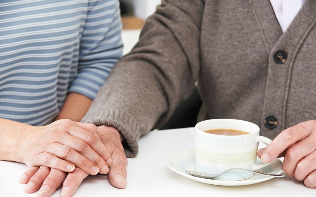 Close Up Of Woman Sharing Cup Of Tea With Elderly Parent