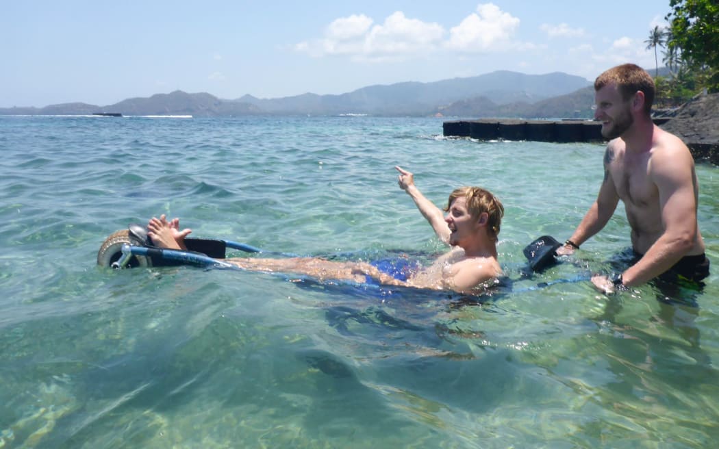 Jacob Riis-Neilsen (left) taking a dip with Jeppe Raven Nielsen in his water going wheelchair.