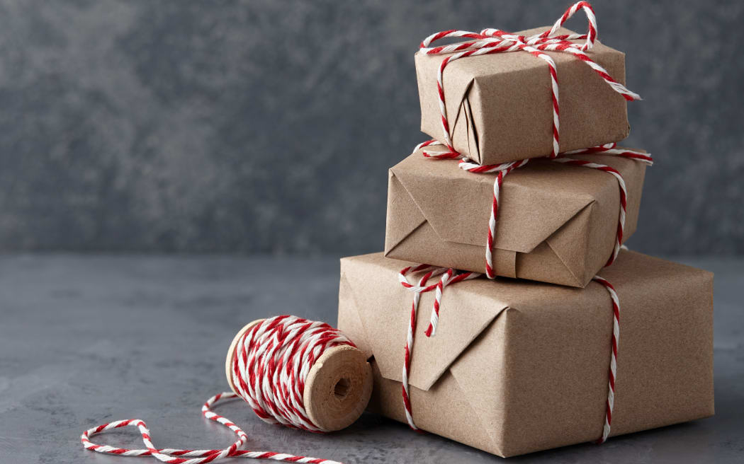 Christmas gift or present boxes wrapped in kraft paper with striped baker's twine string on textured stone background, copy space