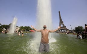 A man cools off in The Trocadero Fountains across from the Eiffel Tower in Paris on 18 June 2022, amid record high temperatures sweeping across France and western Europe.