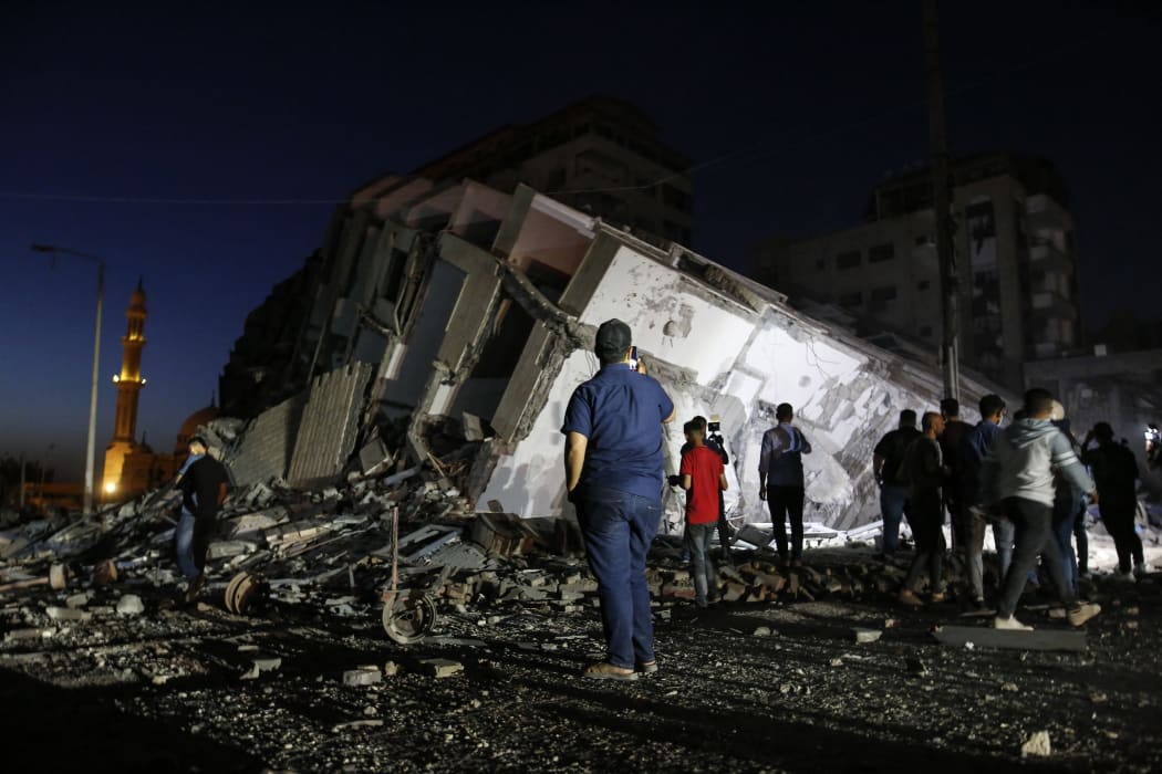 Palestinians gather in front of the rubble of the destroyed 13-storey Hanady Tower after Israeli airstrikes in Gaza City, on 11 May 2021.