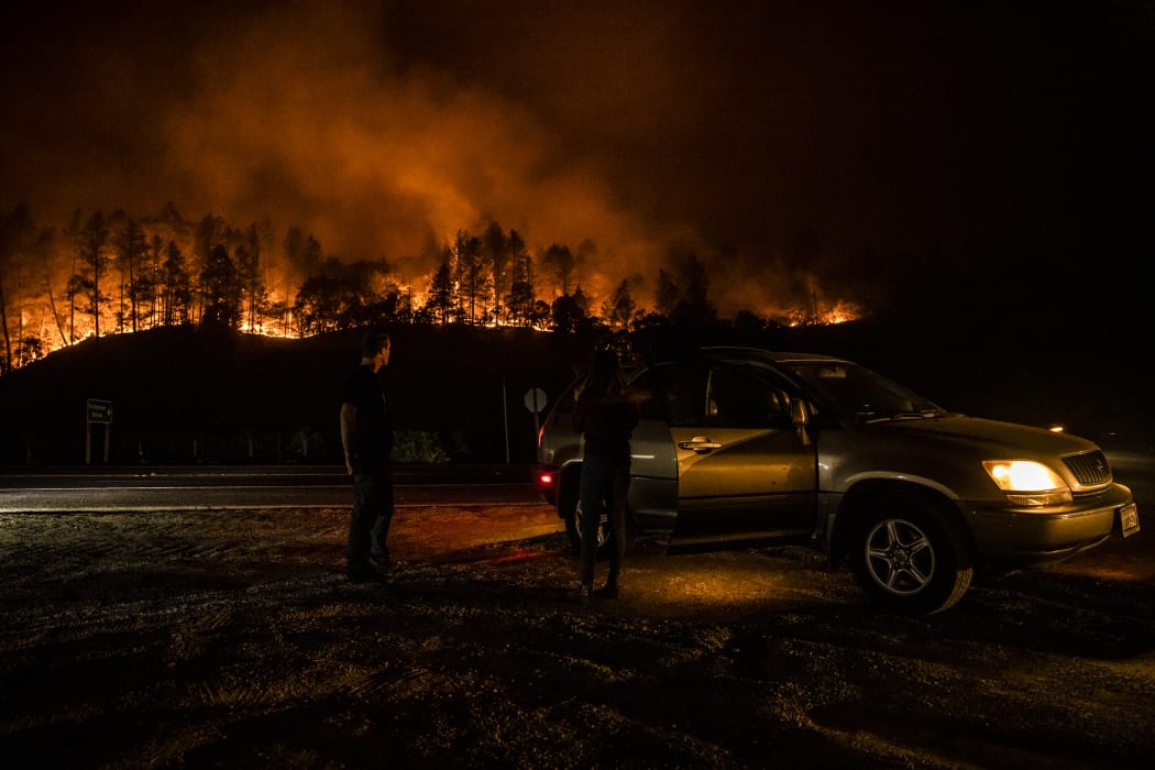 People stop on the side of the road to watch as the Glass Fire slowly blazes down the hill side outside of Calistoga in Napa Valley, California on 28 September 2020.
