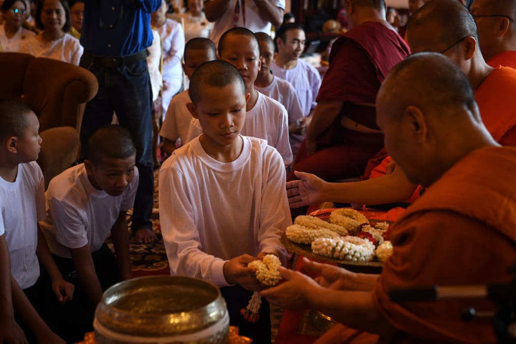 Members of the "Wild Boars" football team hand flower garlands to Buddhist monks during a ceremony to mark the end of their retreat as novice monks at the Wat Phra That Doi Tung temple in the Mae Sai district of Chiang Rai province on August 4, 2018.