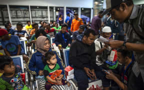 Passengers of a ferry that caught fire gather at Tangjung Perak seaport, after being evacuated, in Surabaya, East Java.