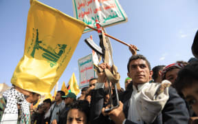 Yemenis lift placards and flags of Lebanon's Hezbollah movement during a rally held in the Houthi-controlled capital Sanaa on September 27, 2024 in protest against Israel's attacks on Lebanon and Gaza.