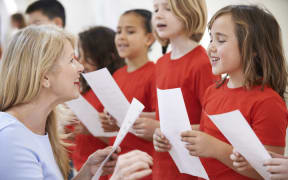 A music teacher helps a group of primary school children singing in a choir (file photo)