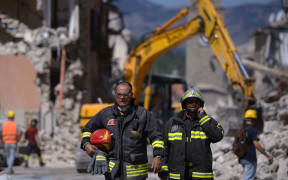 Rescuers coordinate their efforts to free people trapped under the rubble in Amatrice.