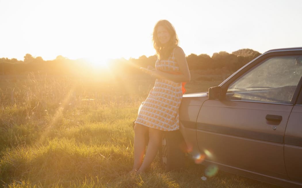 Portrait of mid adult woman leaning against car at sunset (Photo by Axel Bernstorff / Image Source / Image Source via AFP)