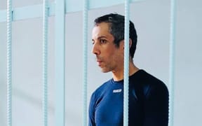 French cyclist Sofiane Sehili, who was arrested on suspicion of crossing the Russian border illegally while attempting to complete his world record attempt for cycling across Eurasia, stands inside a defendants' cage during a court hearing in the far eastern settlement of Pogranichnyy.