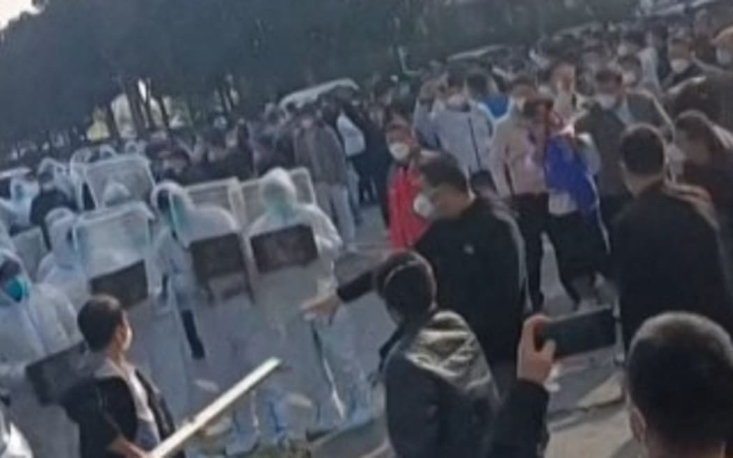 This image grab taken from Afp video footage and posted on November 23, 2022 shows workers at Foxconn’s iPhone factory in Zhengzhou in central China clash with riot police as well as people wearing hazmat suits. The confrontations broke out after employees complained about pay and conditions at the plant.