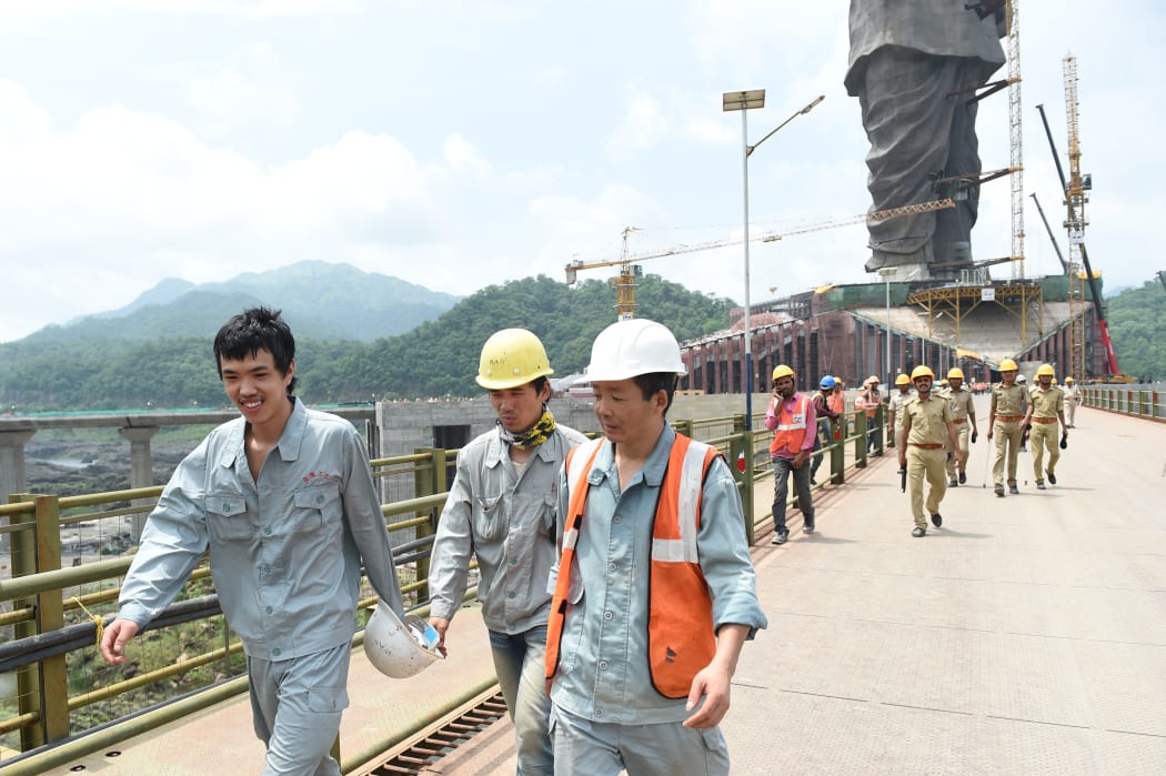 Chinese workers walk near the Statue Of Unity on August 25, 2018, the world's tallest sculpture depicting Sardar Vallabhbhai Patel who was known as 'Iron Man Of India' at Kevadiya Colony region near Narmada Dam, some 200kms. from Ahmedabad. / AFP PHOTO / SAM PANTHAKY