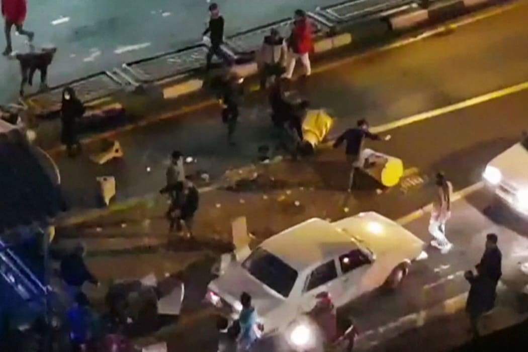 An image grab taken from a handout video released by Iran's Mehr News agency reportedly shows a group of men pushing traffic barriers in a street in Tehran on December 30, 2017.