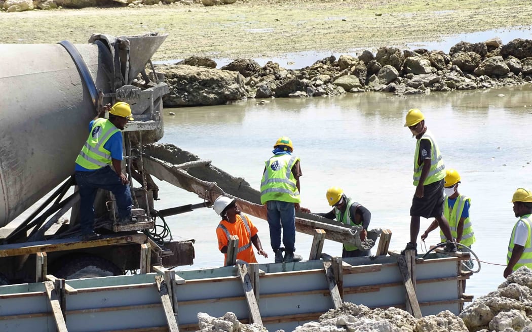 Construction workers with Pacific International Inc. pour concrete for foundations that will support a new track and field and baseball stadium for the upcoming Micronesian Games