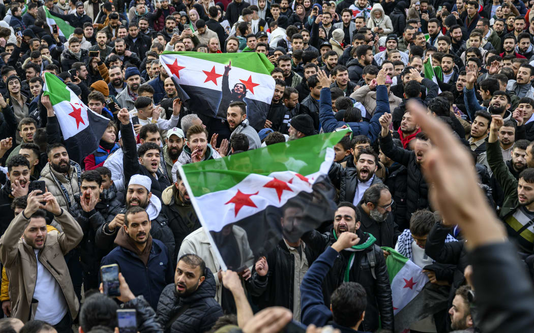 Syrian residents in Turkey wave Syrian flags as they celebrate the end of the Baath rule in Syria after rebel fighters took control of Damascus overnight, at the Fatih Mosque, in Istanbul, on December 8, 2024.