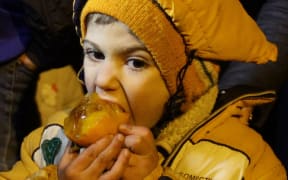 A Syrian child eats a fruit on the outskirts of the besieged rebel-held Syrian town of Madaya.
