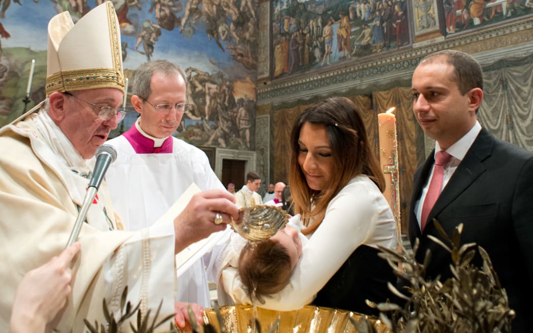 Pope Francis baptising a child in the Sistine chapel.