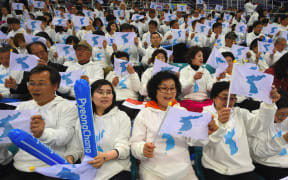 This file photo taken on April 06, 2017 shows South Korean fans waving "unification flags" as they cheer for North Korean players during the IIHF women's world ice hockey championships division II group A competition match between South Korea and North Korea in Gangneung.